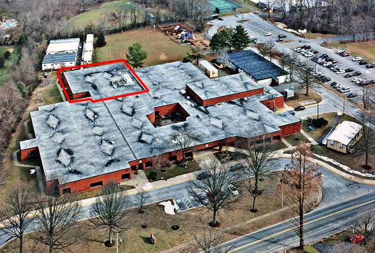 Aerial photograph of Forestville Elementary School. The building is seen from a vantage point above Utterback Store Road, looking east. Several trailers and modular buildings are visible around the school. A portion of the rear of the building has been highlighted with a red outline.