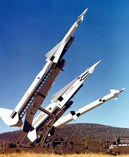 Color photograph of three types of Nike missiles on launchers.